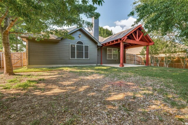 back of property with a chimney, a fenced backyard, and a patio area