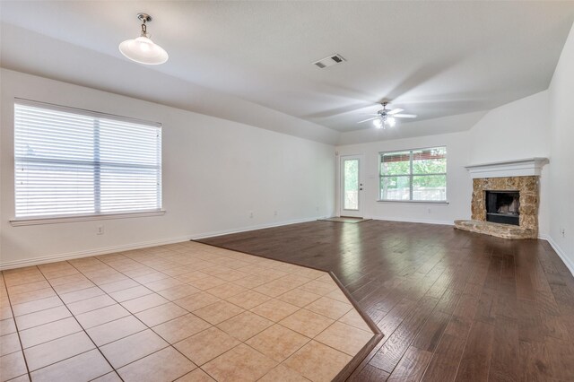 unfurnished living room with a ceiling fan, visible vents, a high end fireplace, baseboards, and wood-type flooring