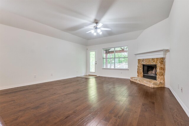 unfurnished living room featuring baseboards, ceiling fan, a fireplace, and dark wood-style flooring