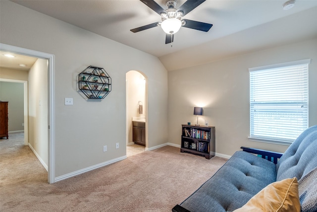 sitting room with ceiling fan, light colored carpet, arched walkways, baseboards, and lofted ceiling
