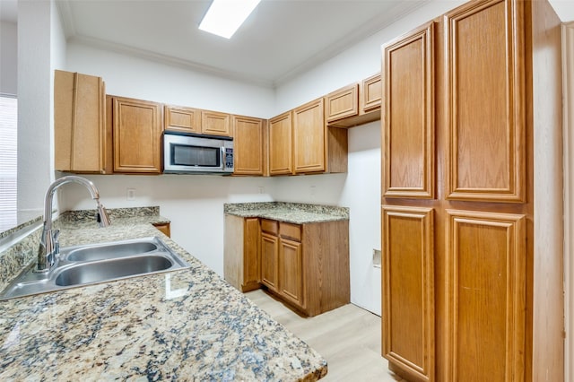 2372 Homewood Ln, Grand Prairie, TX 75050 - kitchen with stainless steel microwave, a sink, crown molding, light wood-type flooring, and brown cabinetry