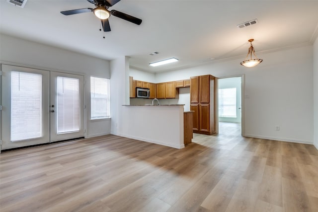 2372 Homewood Ln, Grand Prairie, TX 75050 - kitchen featuring stainless steel microwave, a peninsula, brown cabinetry, french doors, and light wood-type flooring