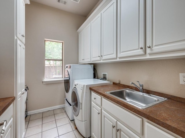 clothes washing area with washer and clothes dryer, cabinet space, baseboards, and light tile patterned flooring