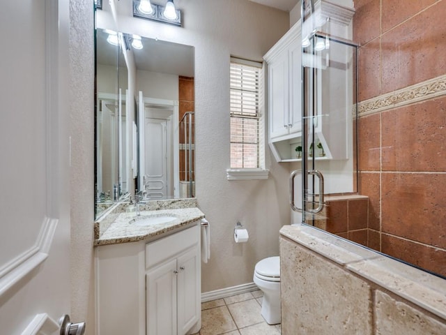bathroom with a shower stall, toilet, tile patterned flooring, vanity, and baseboards