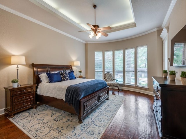 bedroom featuring wood finished floors, crown molding, baseboards, and a raised ceiling
