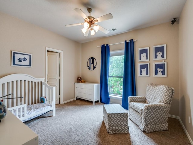 carpeted bedroom featuring a crib, baseboards, and ceiling fan