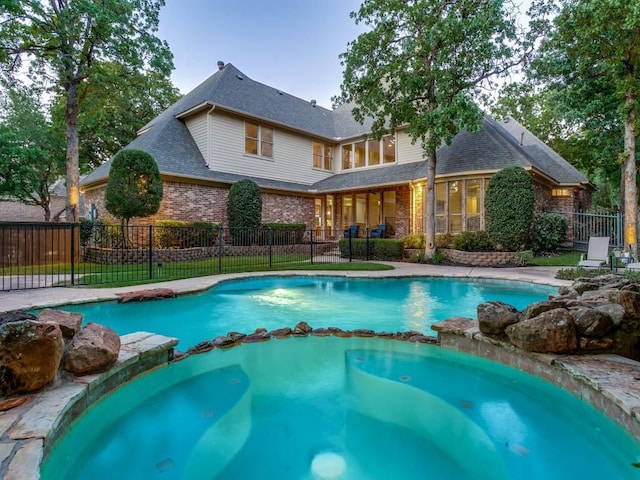 view of swimming pool featuring a pool with connected hot tub and fence