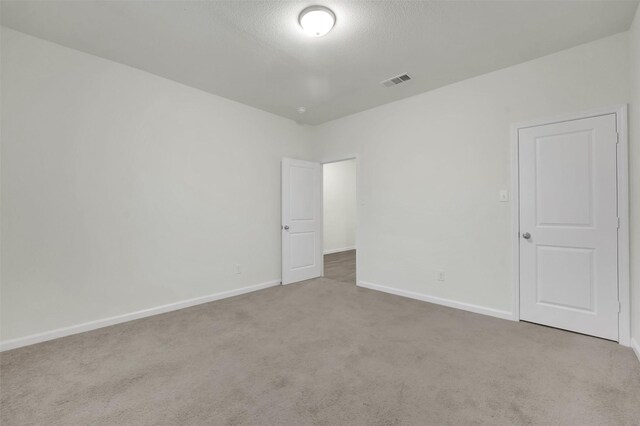 unfurnished bedroom featuring a textured ceiling, baseboards, visible vents, and carpet