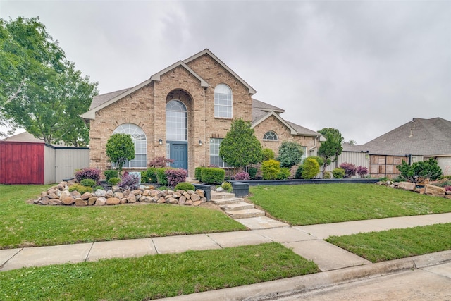 view of front of house with fence, an outbuilding, a front lawn, and brick siding