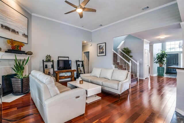 living area with a ceiling fan, visible vents, crown molding, wood finished floors, and stairs