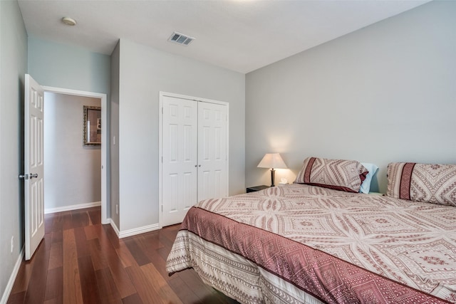 bedroom with baseboards, visible vents, wood finished floors, and a closet