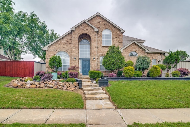 traditional-style home featuring brick siding, fence, and a front yard