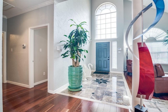 foyer featuring crown molding, baseboards, a textured wall, and wood finished floors