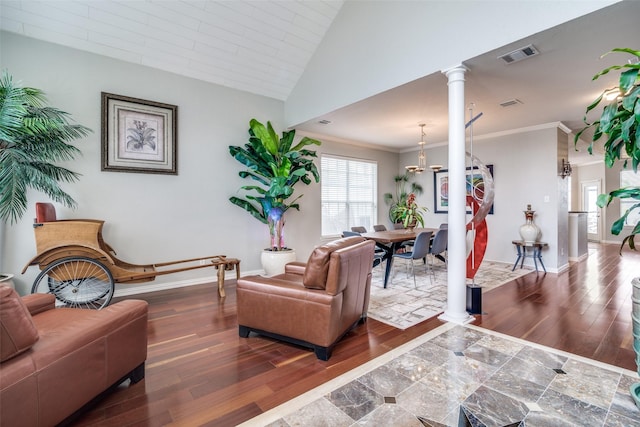 living area with visible vents, crown molding, decorative columns, wood finished floors, and baseboards
