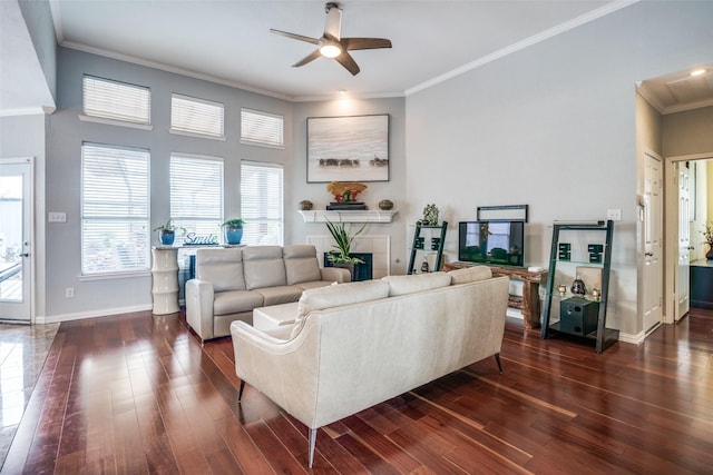 living area featuring ceiling fan, a fireplace, ornamental molding, and dark wood-style floors