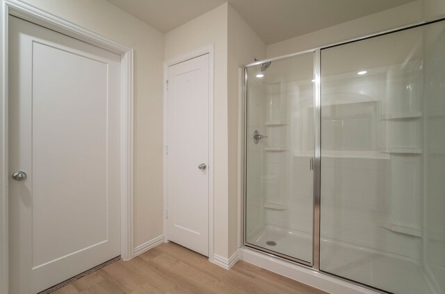 full bath with baseboards, a stall shower, and wood finished floors