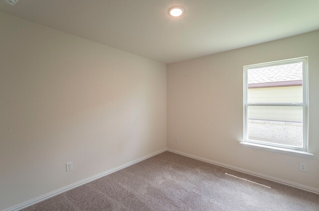 carpeted spare room featuring baseboards