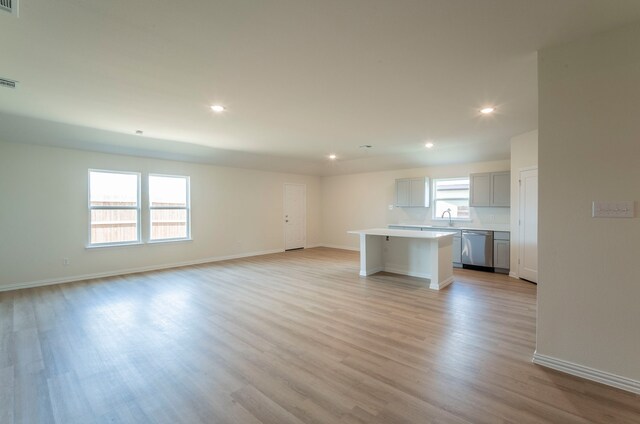 unfurnished living room featuring a sink, baseboards, light wood-style floors, and recessed lighting