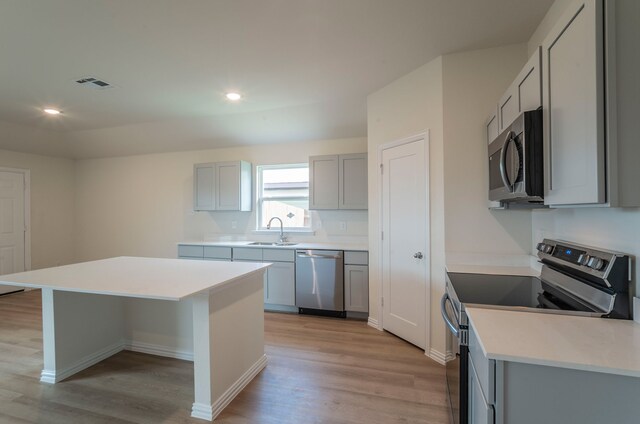 kitchen featuring gray cabinets, visible vents, appliances with stainless steel finishes, a sink, and light wood-style floors