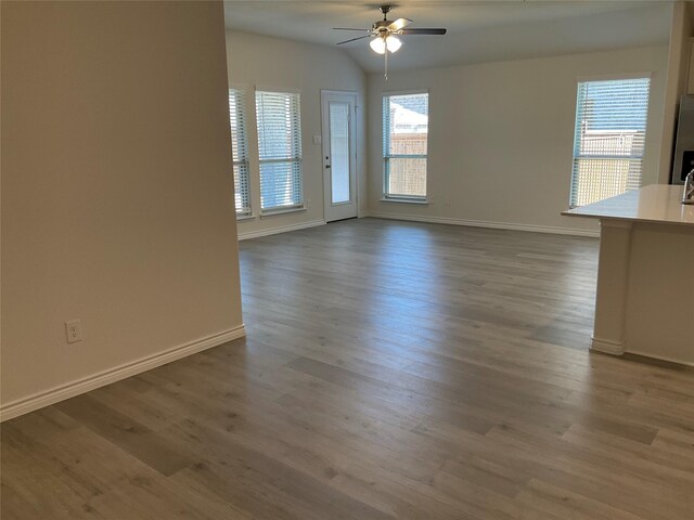 interior space featuring baseboards, ceiling fan, wood finished floors, and lofted ceiling