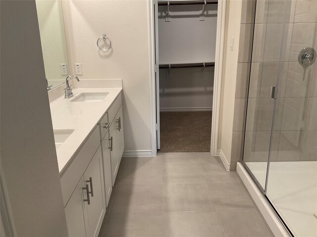 bathroom with a sink, baseboards, a shower stall, and a walk in closet