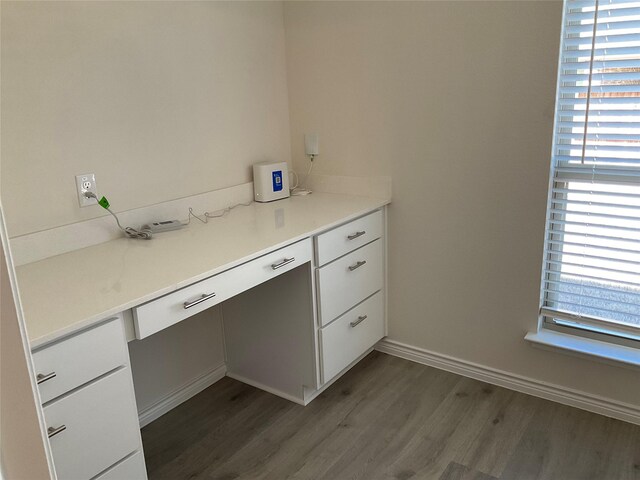 unfurnished office with baseboards, dark wood-style flooring, and a wealth of natural light