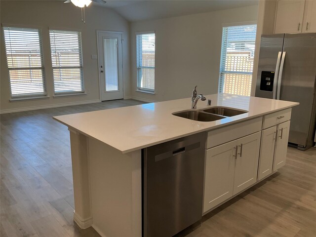 kitchen with a sink, light countertops, open floor plan, stainless steel appliances, and light wood-style flooring