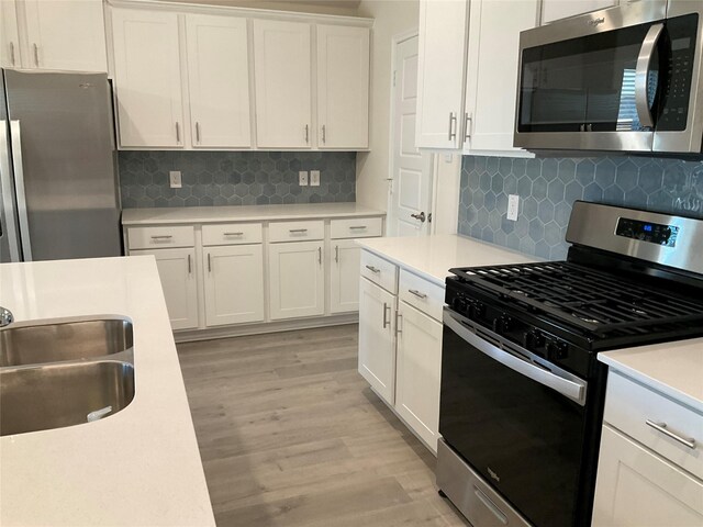 kitchen with light wood-style floors, light countertops, white cabinets, tasteful backsplash, and stainless steel appliances