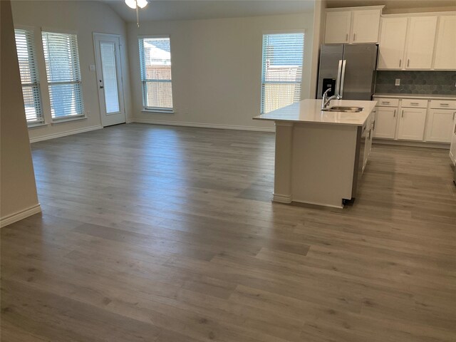 kitchen featuring wood finished floors, baseboards, white cabinetry, stainless steel fridge with ice dispenser, and a sink
