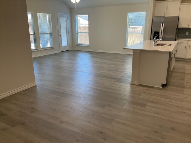 kitchen with a sink, wood finished floors, white cabinets, and stainless steel fridge with ice dispenser