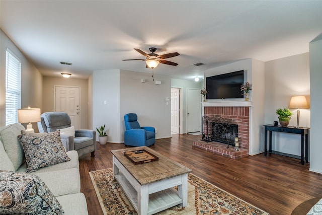 living area featuring a ceiling fan, visible vents, wood finished floors, and a fireplace