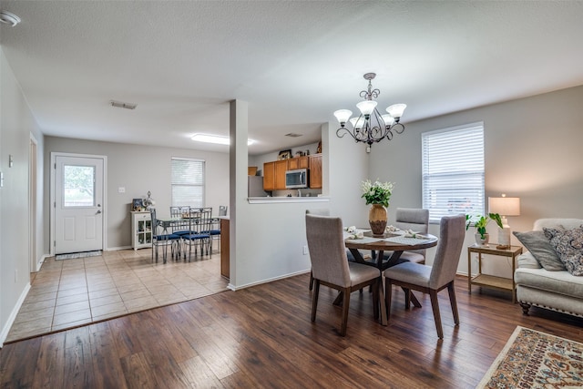 dining area with an inviting chandelier, baseboards, dark wood finished floors, and visible vents