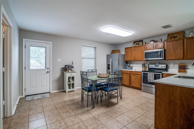 kitchen featuring visible vents, appliances with stainless steel finishes, brown cabinets, a sink, and light countertops