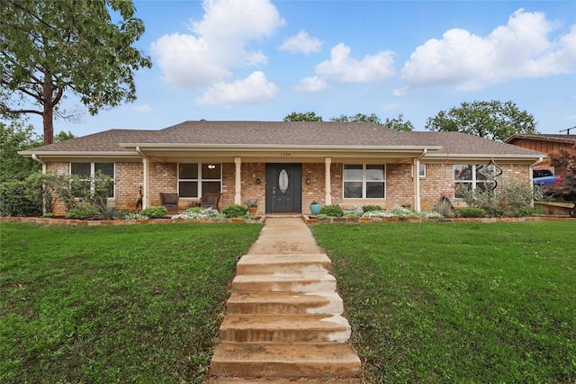 single story home featuring covered porch, a front yard, and brick siding