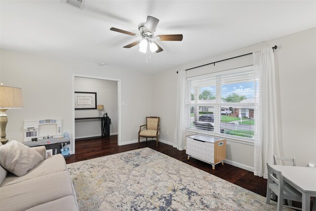 living area featuring dark wood-style flooring, ceiling fan, visible vents, and baseboards