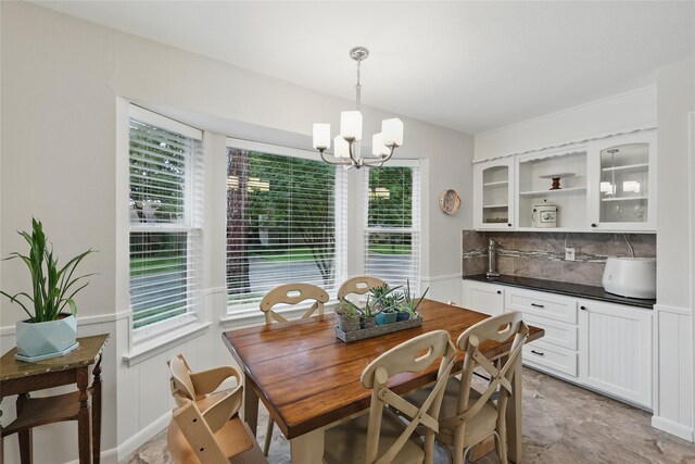 dining area featuring a wainscoted wall and a notable chandelier