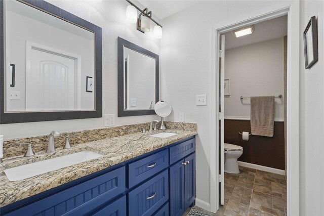 bathroom with baseboards, a sink, stone finish floor, and toilet