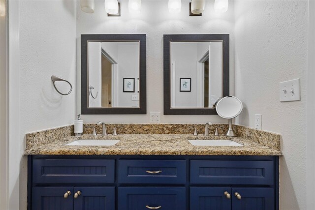 bathroom with double vanity, a sink, and a textured wall