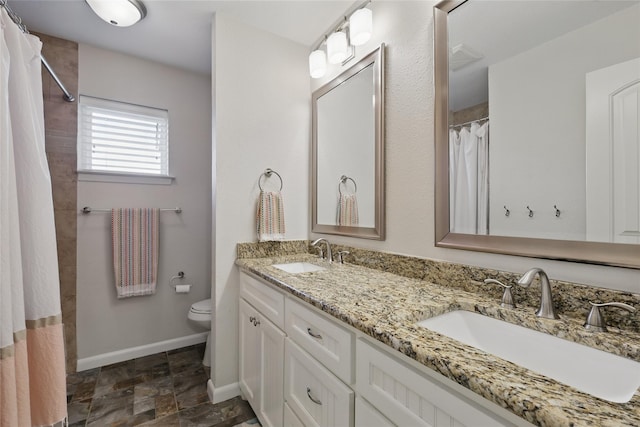 full bath with double vanity, a sink, stone finish floor, and toilet