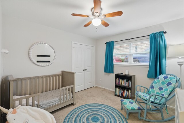 bedroom featuring a ceiling fan, a nursery area, baseboards, a closet, and carpet