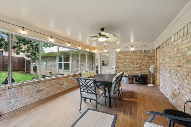 sunroom / solarium featuring rail lighting, outdoor dining space, and a ceiling fan