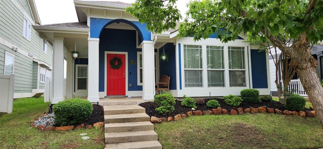 view of exterior entry with a lawn and stucco siding