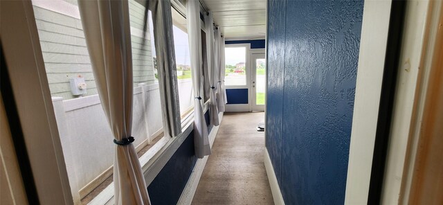 corridor with baseboards, a textured wall, and wood finished floors