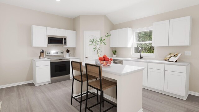 kitchen with light wood-style floors, a kitchen breakfast bar, a center island, a sink, and stainless steel appliances