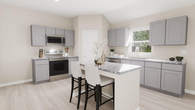 414 Rose Ave, Cleburne, TX 76033 - kitchen featuring gray cabinets, appliances with stainless steel finishes, a sink, light wood-style floors, and a breakfast bar