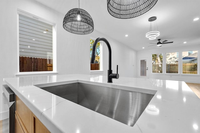 room details with light stone counters, a sink, ceiling fan with notable chandelier, recessed lighting, and decorative light fixtures