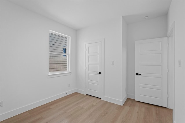unfurnished bedroom with baseboards and light wood-style flooring