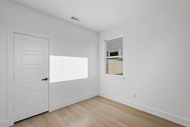 unfurnished room with baseboards, light wood-type flooring, and visible vents