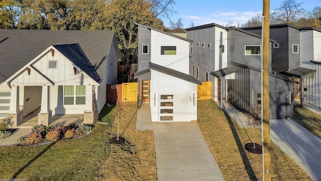 view of front of house with a gate, board and batten siding, fence, and driveway