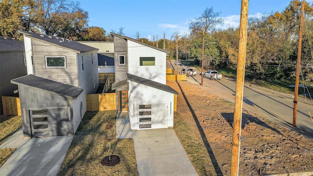 view of front of home featuring a garage, fence, and concrete driveway